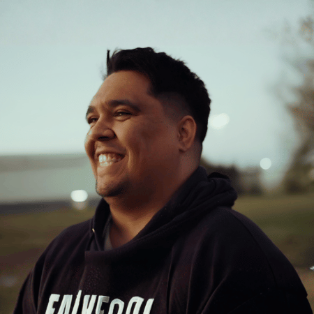 Willmunro - 1 - edited - Yalari - Yalari Candid portrait of a man with short dark hair smiling outdoors wearing a dark hoodie with a blurred background behind him yalari yalari