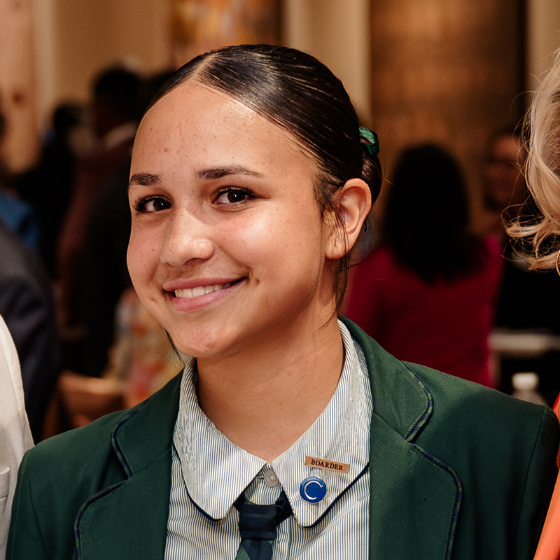 Smiling student in a green blazer and striped shirt at a school event portrait orientation   yalari   yalari